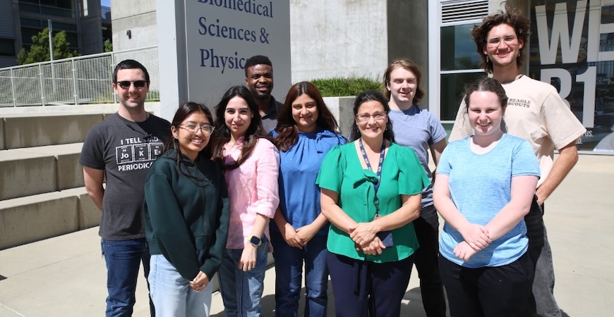 Pictured are Professor Eva de Alba and members of her lab standing outside the Biomedical Sciences & Physics building at UC Merced.