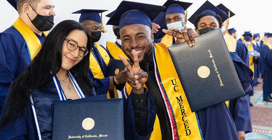 UC Merced graduating students pose for a photo with their regalia.